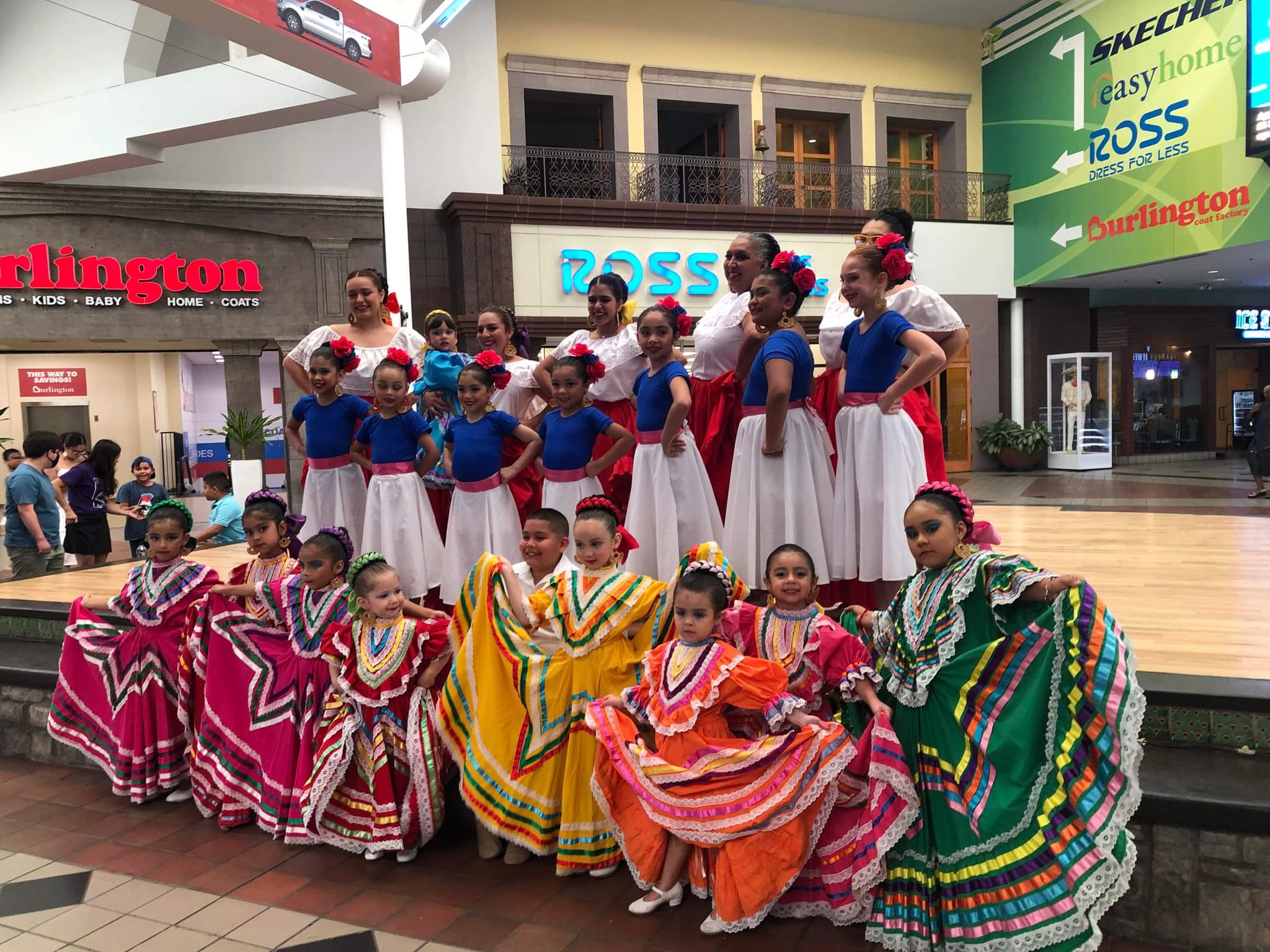 Group of Folklorico dancers posing for a photo on a stage inside a mall